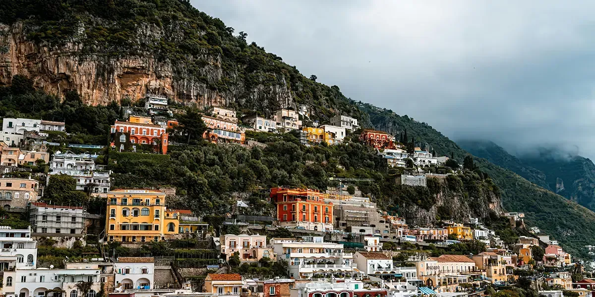 Vibrant hillside houses stacked along the dramatic cliffs of the Amalfi Coast under a cloudy sky in southern Italy.Colorful hillside houses on the Amalfi Coast, Italy.