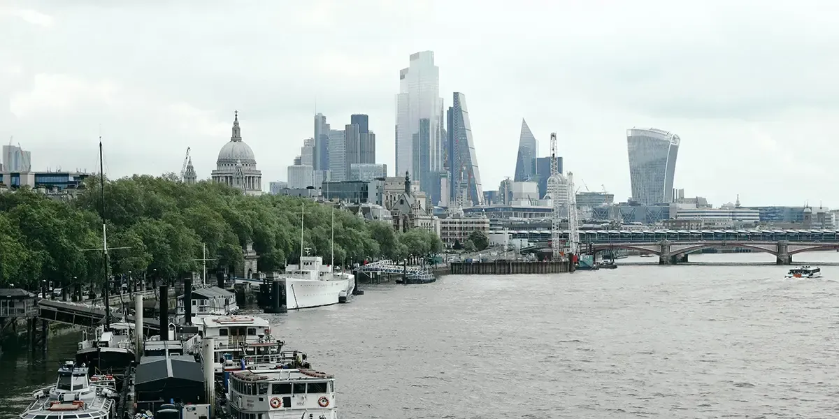 Boats docked along the Thames with London skyscrapers in the background.