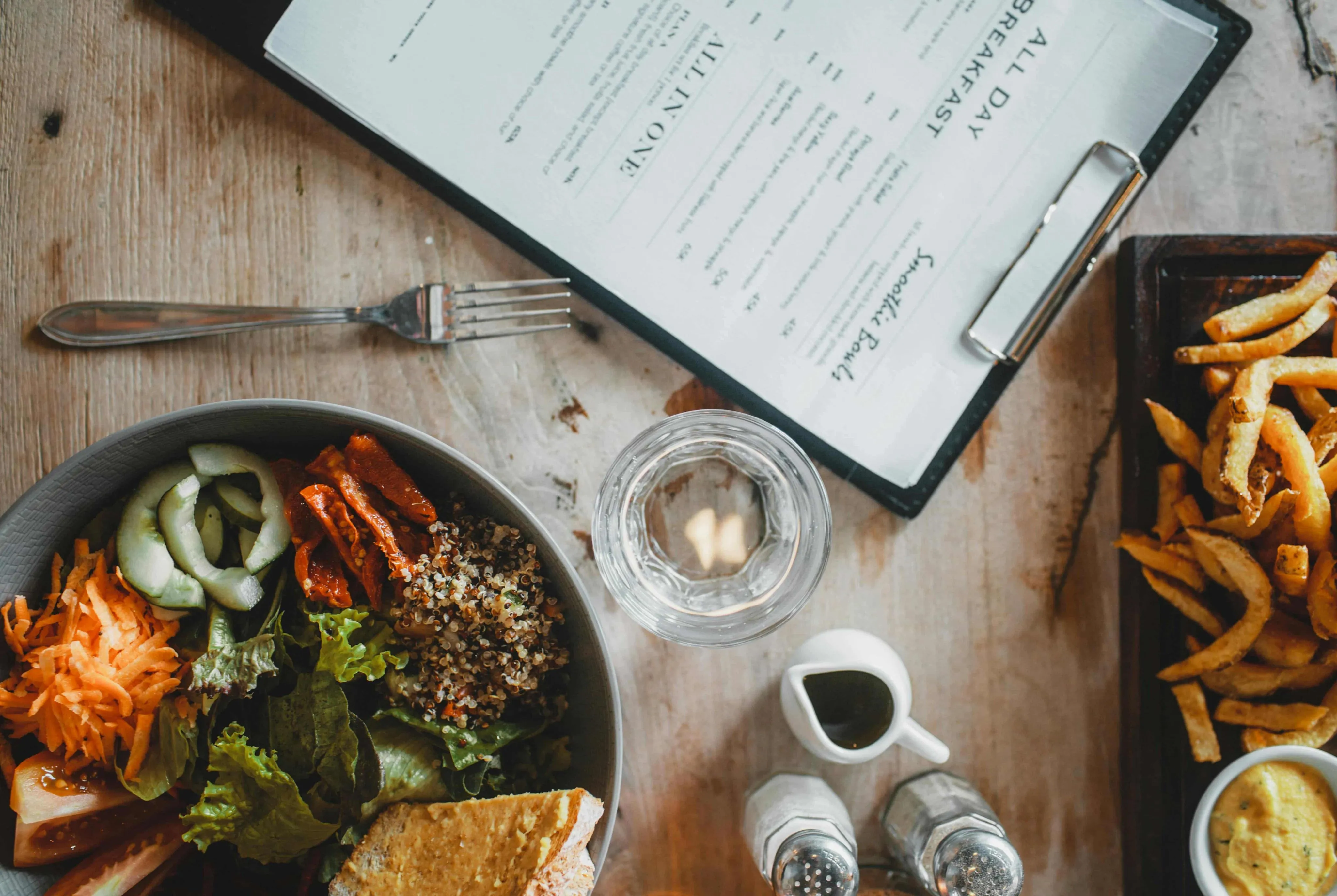 How to Order Food A wooden table with a plate of salad, a glass of water, and a menu