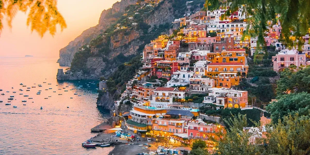 Colorful houses of Positano cascading down a cliff at sunset.