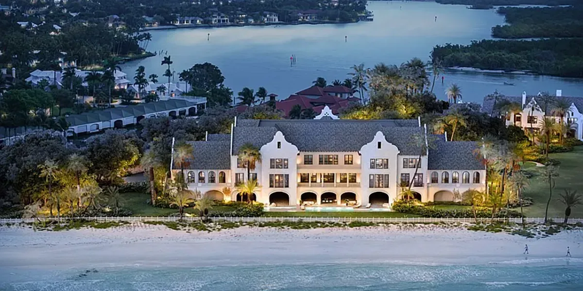 Gordon Pointe estate in Naples, Florida, illuminated at dusk with beachfront access and private bay in the background