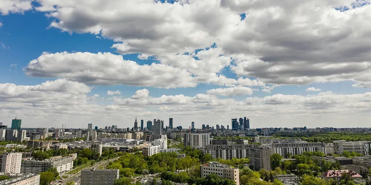 Aerial view of Warsaw with high-rise buildings and a wide cloudy sky.