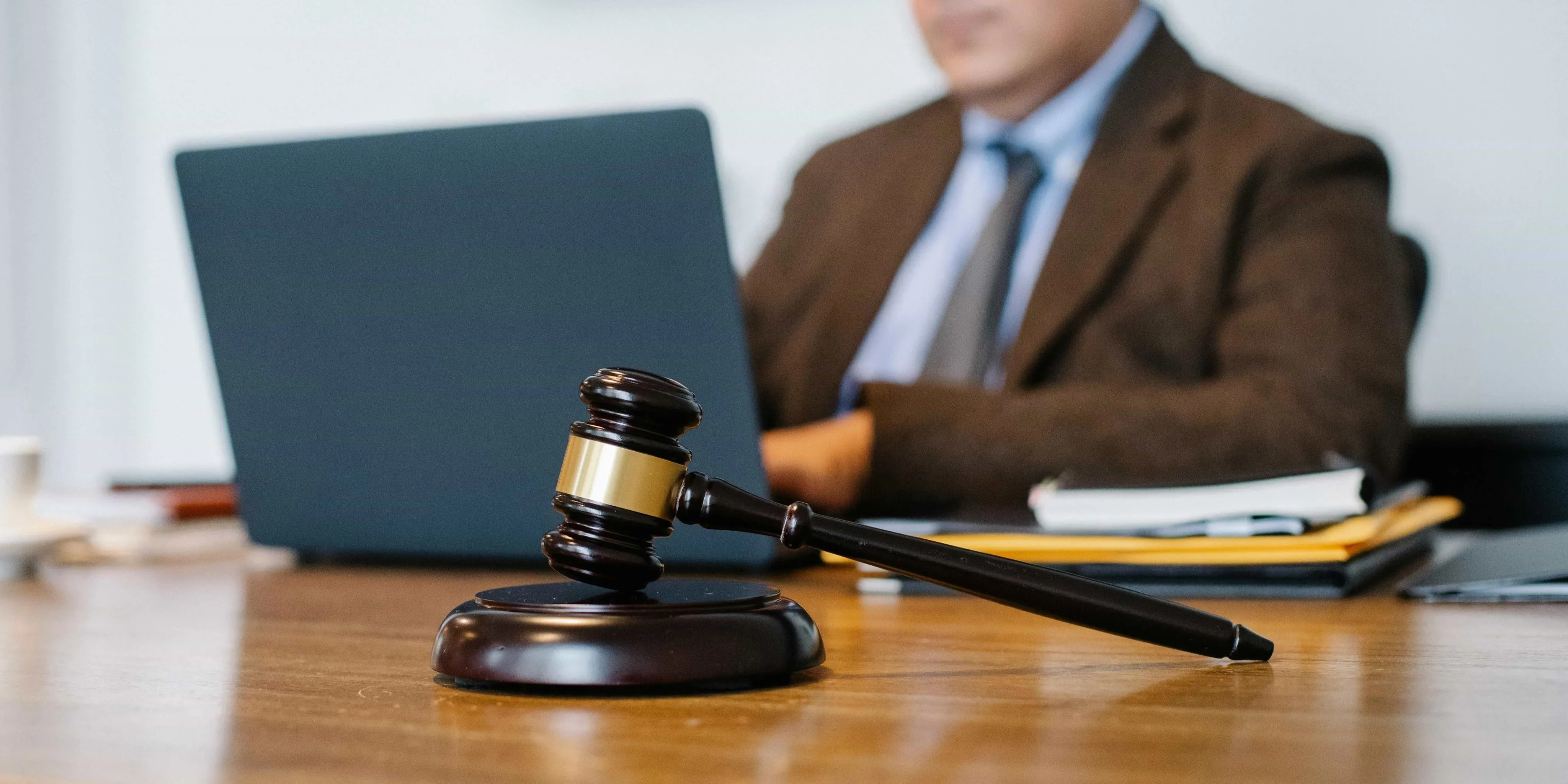 Find A Reliable Lawyer Wooden judge's gavel on a desk with a blurred lawyer working