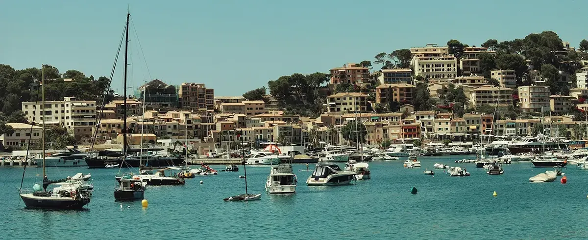 Boats anchored in a harbor near a residential town in Spain.