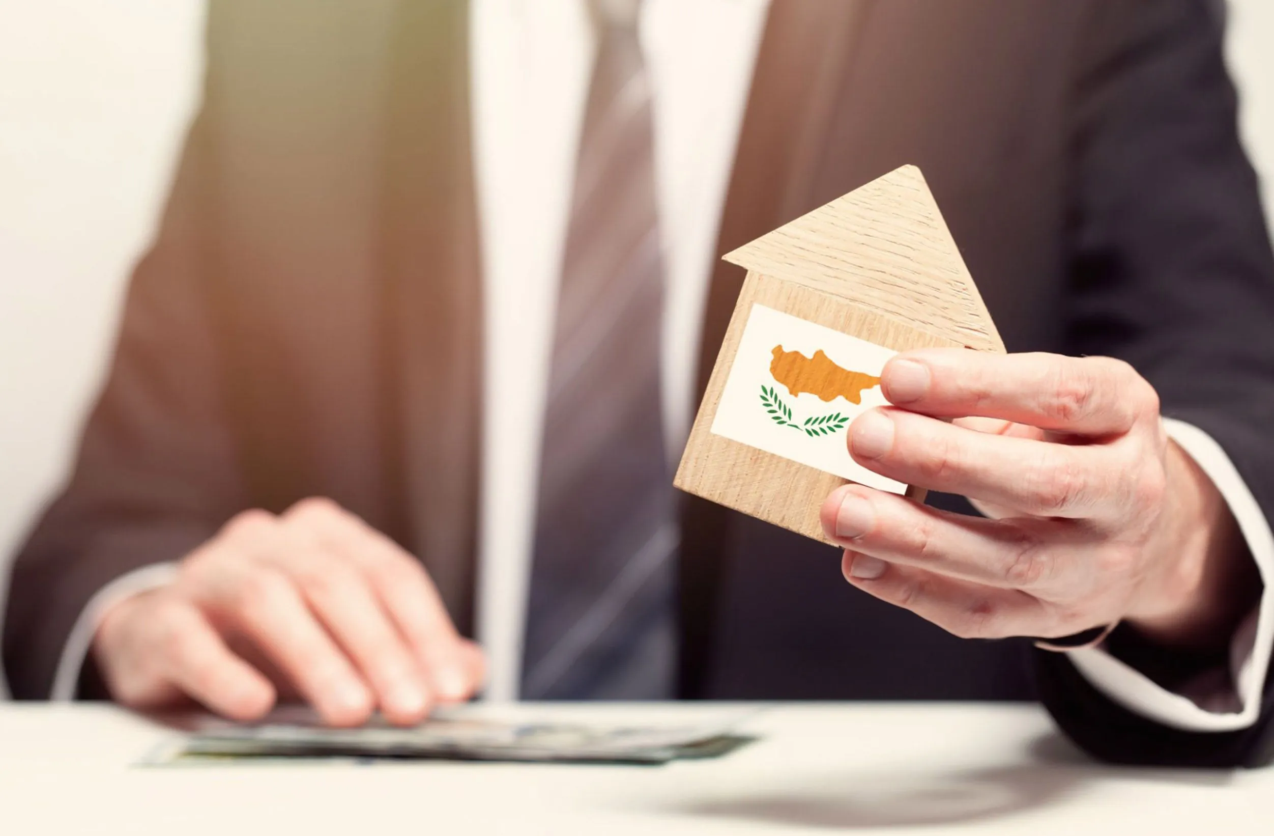 Businessman hand holding wooden home model with Cyprus flag. insurance and property concepts